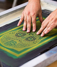 Hands pulling ink across a screen-printing frame